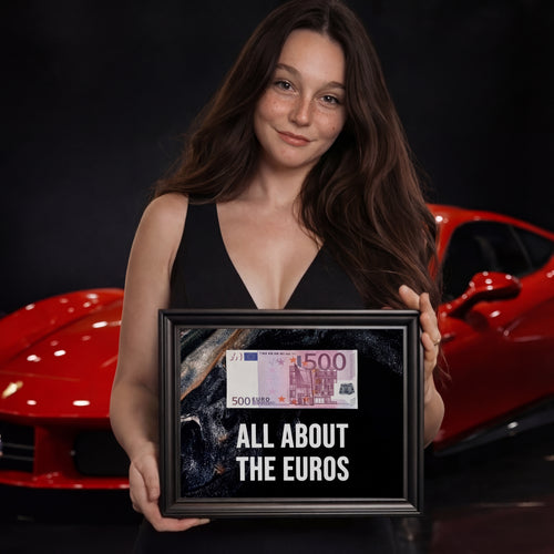 Fiatal nő egy "ALL ABOUT THE EUROS" feliratú, 500 eurós bankjeggyel díszített 3D képkeretet tart egy Ferrari előtt.